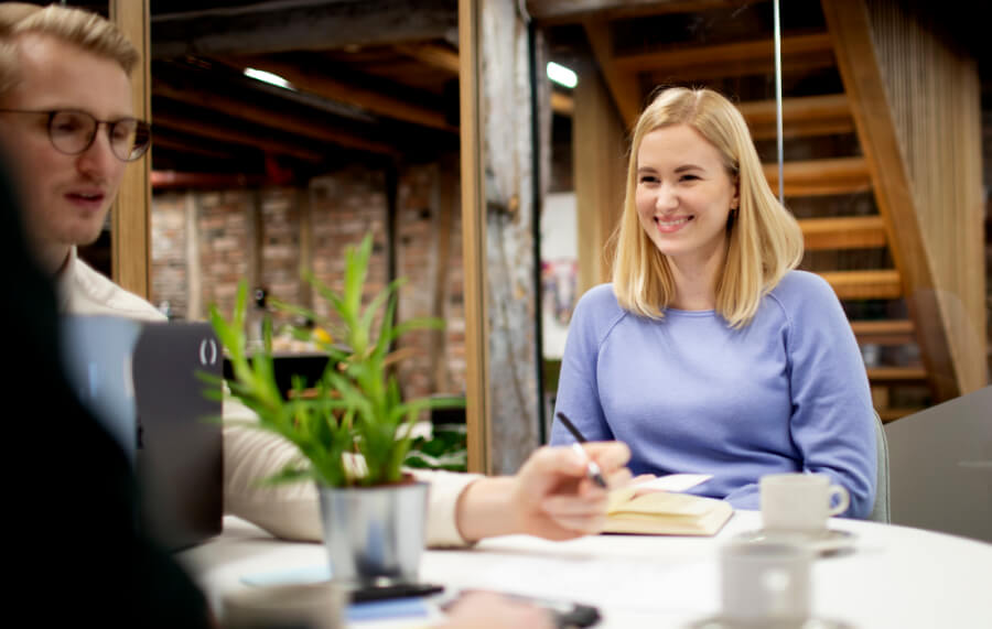 Workshop rundt et bord, med en smilende Vanessa og en fokusert Roland med penn i hånd.